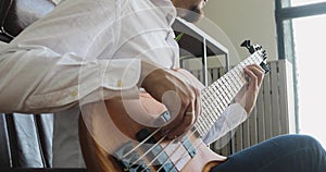 Businessman is playing on guitar and enjoying it sitting in office, side view.