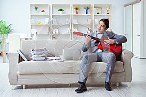 The businessman playing guitar at home