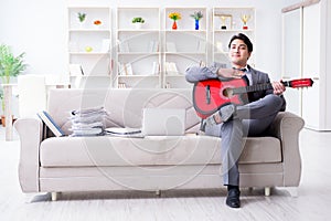 The businessman playing guitar at home