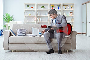 The businessman playing guitar at home