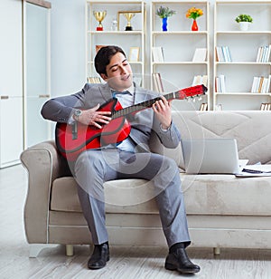 Businessman playing guitar at home