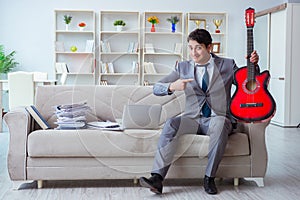 The businessman playing guitar at home