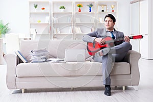 The businessman playing guitar at home