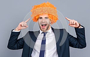 Businessman point finger on crazy wig. Business party. Business man at corporate party isolated on grey. Corporate fun