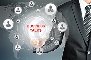 Businessman pointing on BUSINESS TALKS sign on virtual screen photo