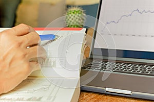 Businessman pointing on data chart with pen while working iwith laptop.