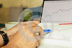 Businessman pointing on data chart with pen while working iwith laptop.