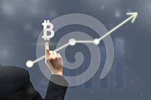 Businessman pointing digital bitcoin icon. Chart and diagram, graph of growing rate bitcoin prices. Virtual cryptocurrency stock