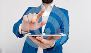 Businessman with pointing finger in front of him. Businessman holds lap top in hand and points with his finger.