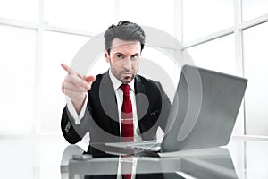 Businessman pointing the finger at you,sitting at his Desk