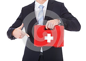 Businessman pointing at first aid box