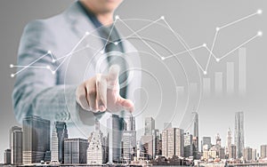 Businessman pointing his finger and touch the screen with building foreground and financial info-graphic