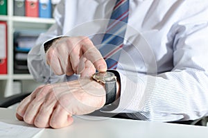 Businessman pointing his watch with his finger