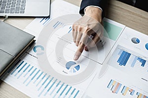 Businessman pointing to a pie chart on the document, he is examining the data from the finance documents