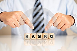 Businessman pointing to the wooden blocks with the word 'kasko' written on it