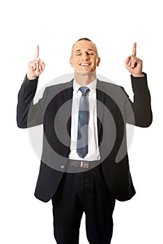 Businessman pointing upwards and smiling at camera