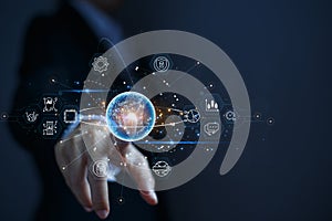 Businessman pointing at a virtual globe with business related icons around it. The concept of connecting the business world by