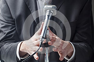 Businessman or politician speaking up on microphone