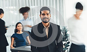 Businessman portrait poses confidently in busy meeting room. Concord