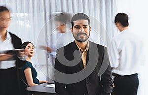 Businessman portrait poses confidently in busy meeting room. Concord