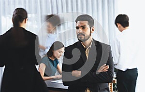 Businessman portrait poses confidently in busy meeting room. Concord