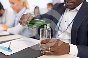 Businessman pouring water to glass at conference