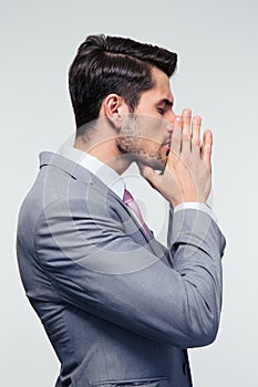 Businessman praying over gray background