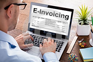 Businessman Preparing E-Invoicing Bill On Laptop At Desk photo