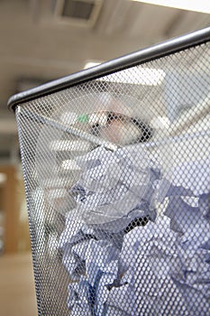 Businessman preparing to throw paper into wastepaper bin, close up on wastepaper bin photo