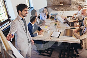 Businessman presenting her colleagues business strategy on whiteboard during a meeting in the office