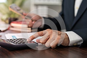 Businessman is pressing the calculator calculate the various costs that must be paid by the bill. Many invoices held and placed on