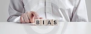 Businessman pressing his finger on the wooden cubes with the word bias. Racial or gender prejudice in workplace photo