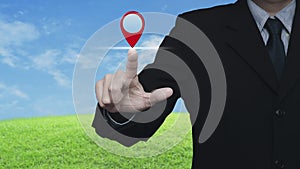 Businessman pressing map pin point location button over green grass field with blue sky, Map pointer navigation online concept