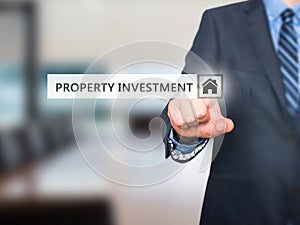 Businessman pressing Property Investment button on virtual scre