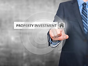 Businessman pressing Property Investment button on virtual scre