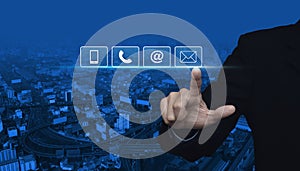 Businessman pressing telephone, mobile phone, at and email buttons over city tower and street blue tone background, Customer supp