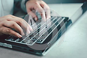 Businessman or programmer using laptop with triangle caution warning sign
