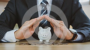 Businessman protect the piggybank in hand, donation, saving, charity, family finance plan concept, fundraising, superannuation,