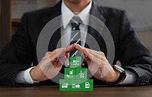 Businessman protecting and covering over wooden block that have H2 icons. Concept of clean hydrogen energy, Renewable fuel green