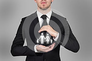 Businessman protecting family papercut with his hands