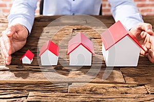 Businessman Protecting The House Models With Hands