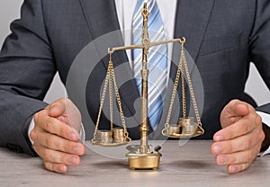 Businessman protecting justice scale with coins