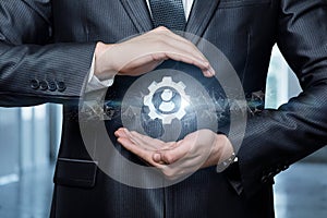 A businessman protects with a gesture a gear icon with a person
