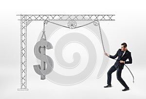 Businessman pulling big concrete 3d dollar sign with drawn pulley isolated on white background