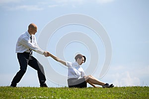 Businessman pulling businesswoman's hand in park