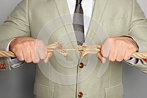 Businessman pulling frayed rope in opposite directions