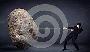 Businessman pulling huge rock with a rope