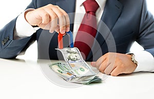 Businessman pulling money from stack on table with the magnet