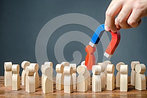 businessman pulls out a red figure of a man from the crowd with the help of a magnet. Increase team efficiency, productivity.