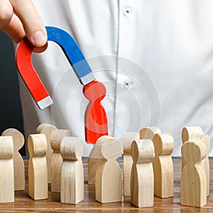 businessman pulls out a red figure of a man from the crowd with the help of a magnet. leader manages the business and forms a team photo
